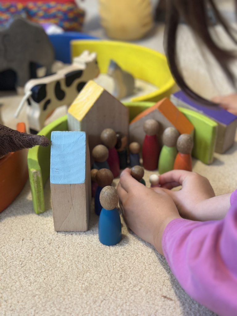 ahşap figürler ve onlarla oynayan çocuk elleri